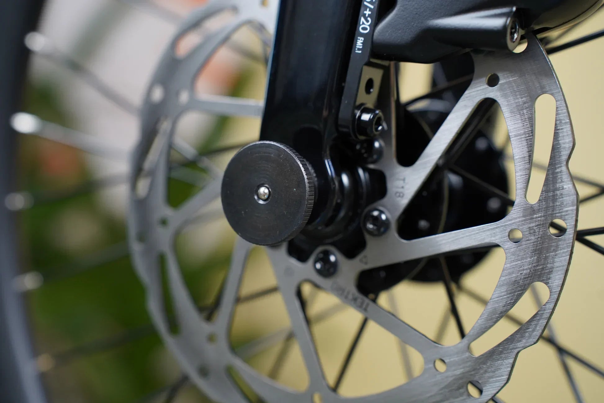Close-up of a bicycle disc brake rotor and magnetic buckle on black fork