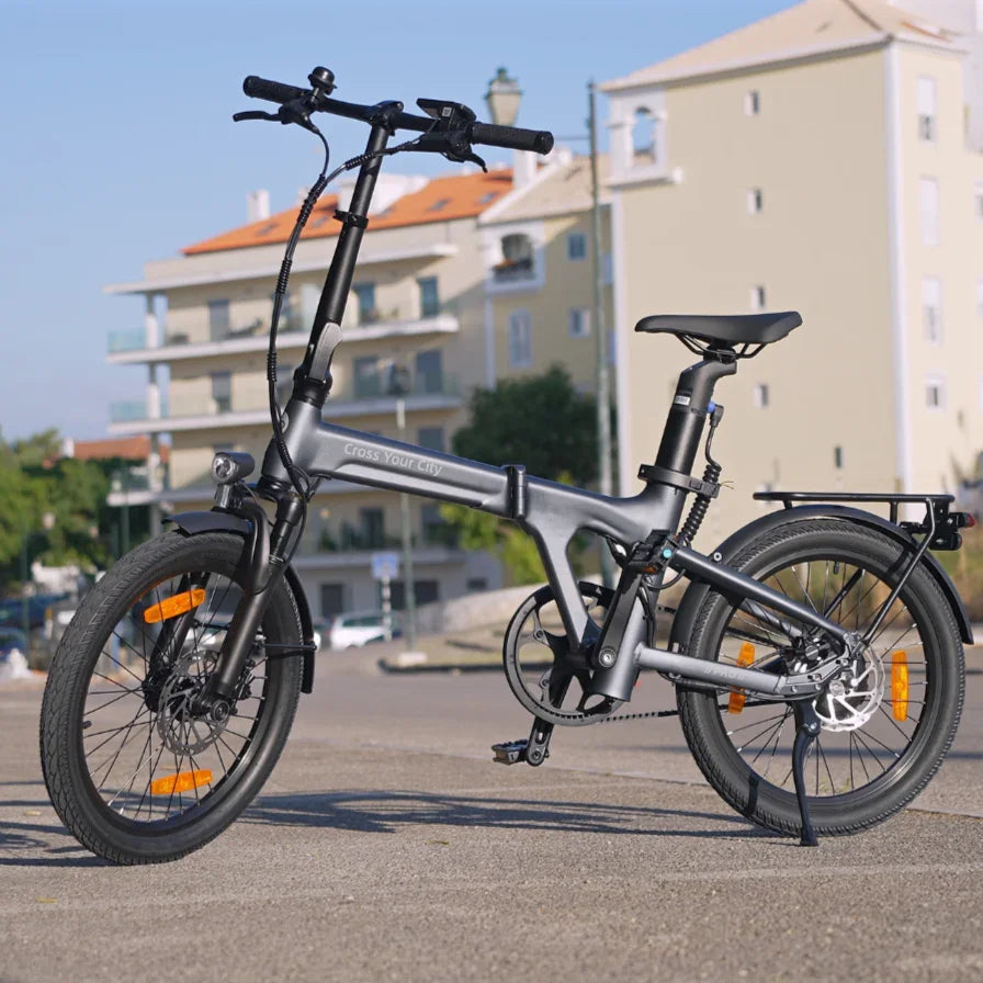 Foldable electric bike with gray frame, disc brakes, rear rack, and city background