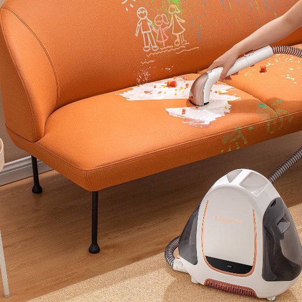 Hand using Uwant B100 carpet spot cleaner to remove food stains and crayon marks from orange sofa upholstery