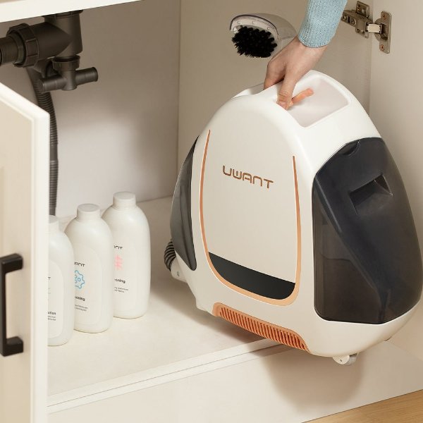 Hand placing Uwant portable carpet spot cleaner inside a white cabinet with cleaning solution bottles